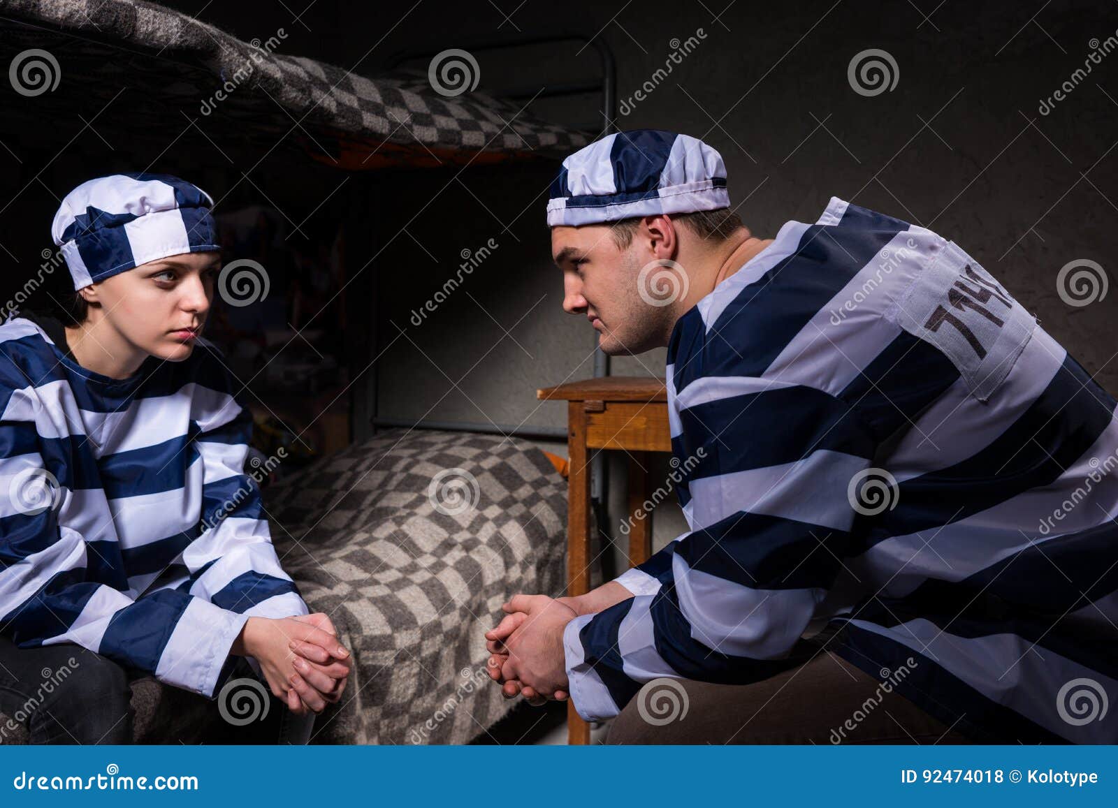 young male and female prisoners wearing prison uniform sitting a