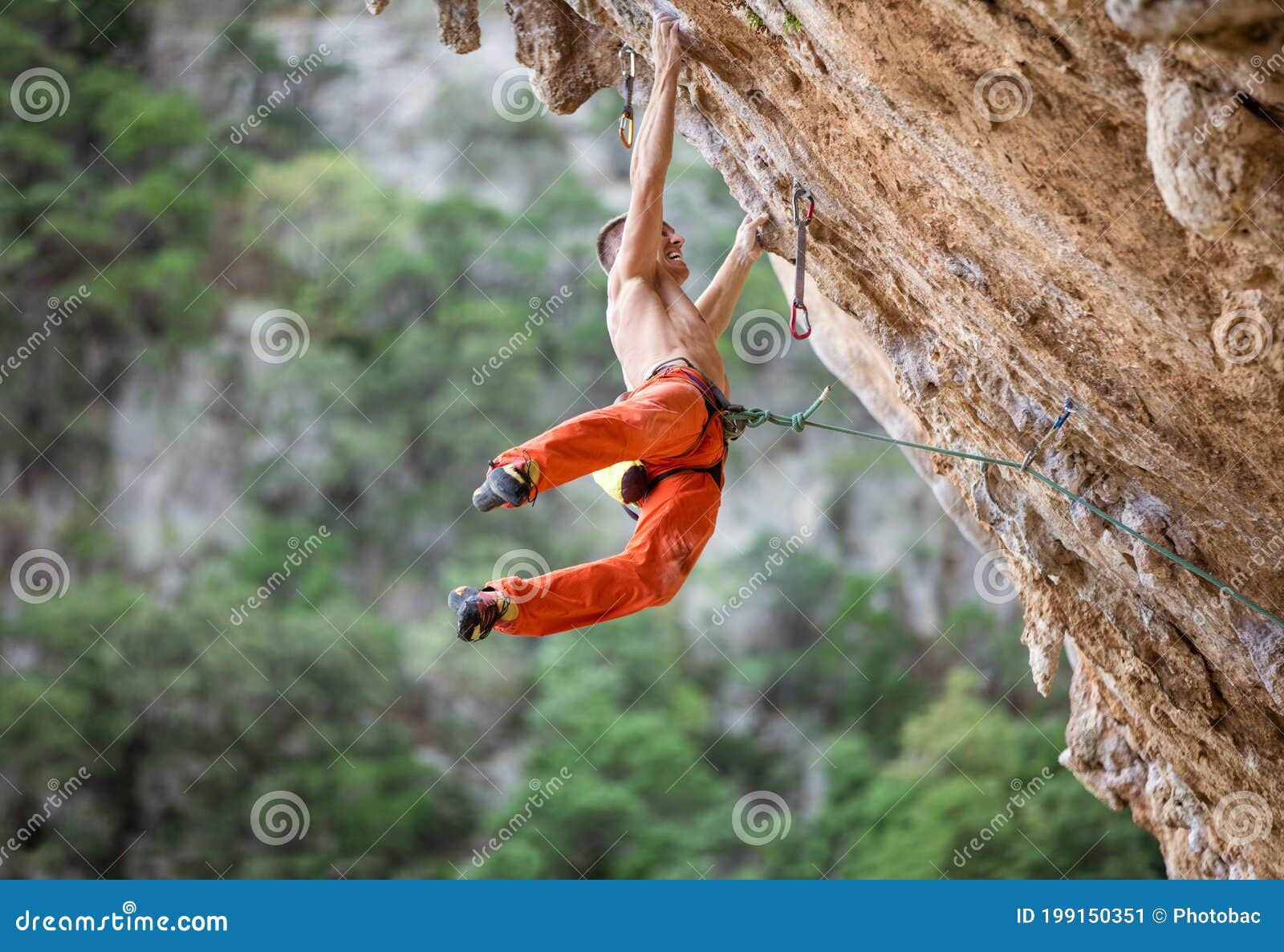 young male rock climber after jumping and gripping small handholds