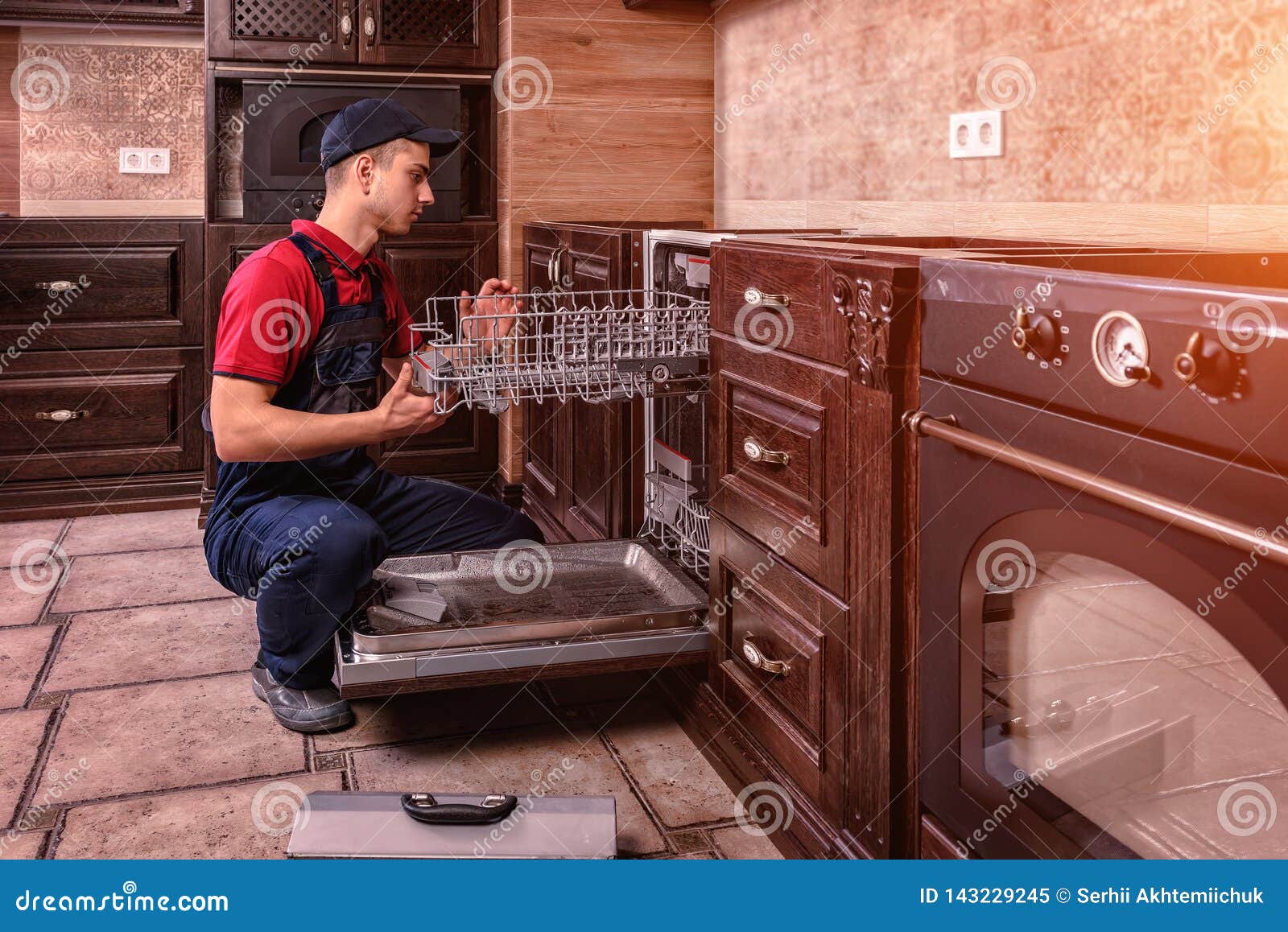Young Male Technician Repairing Dishwasher in Kitchen Stock Image