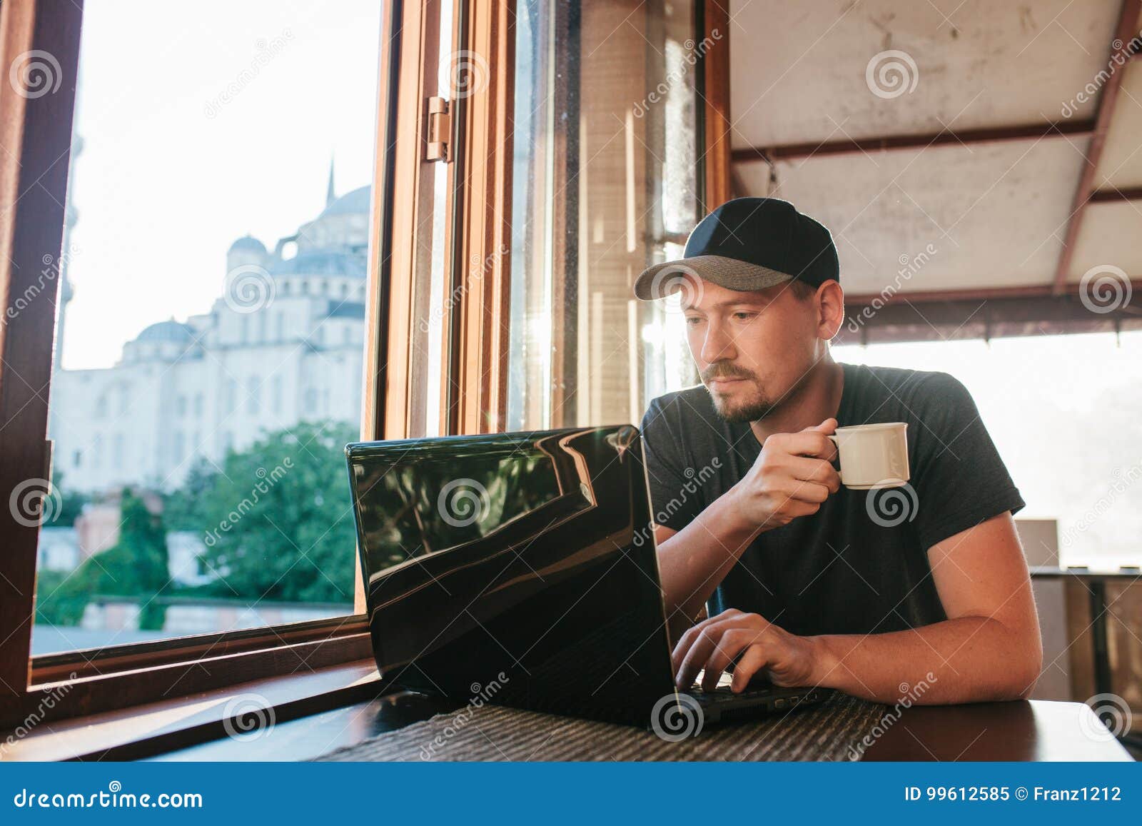 a young male tourist blogger freelancer working on a laptop in a cafe in istanbul. a view from the window to the world