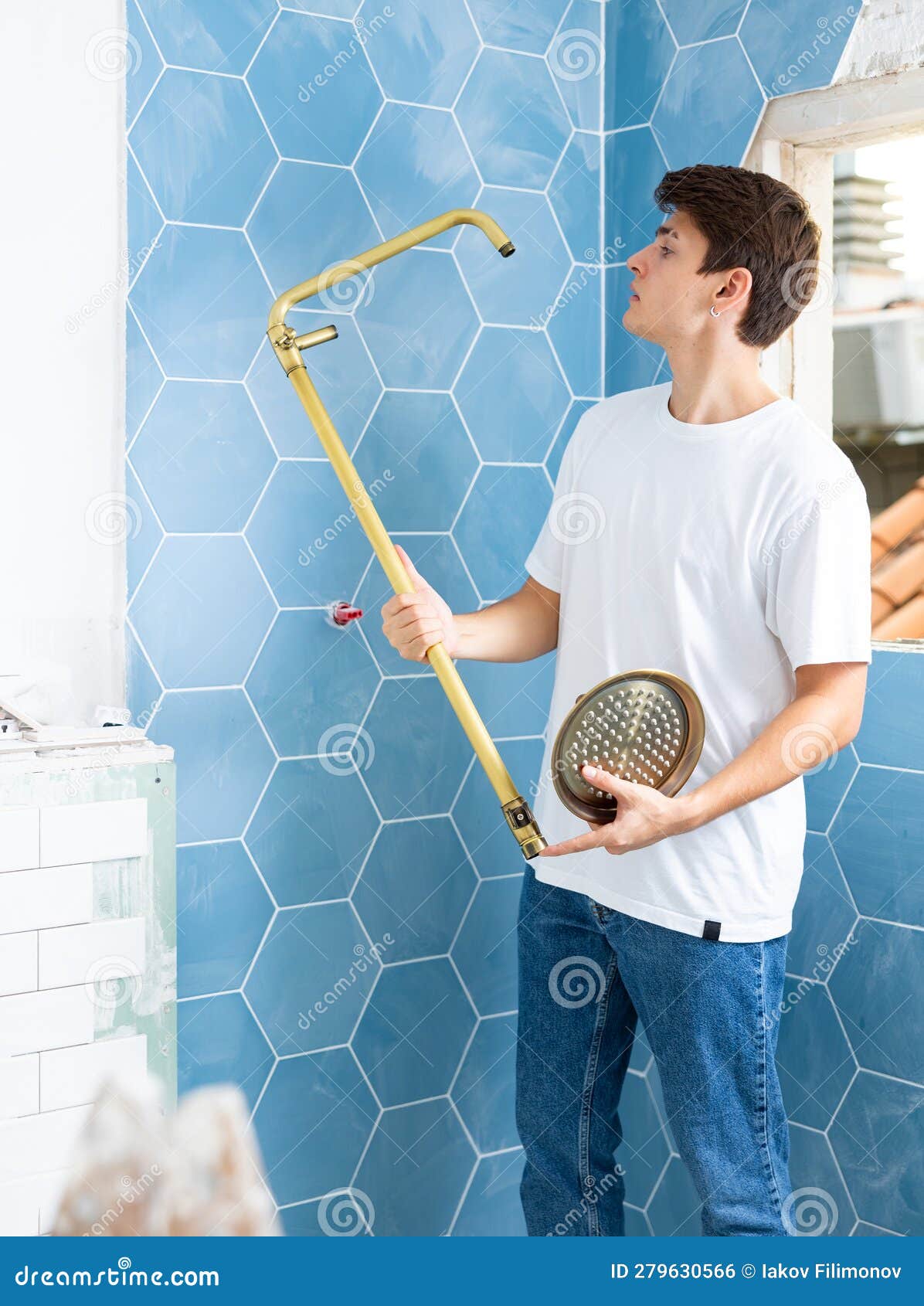 Young Man Assembles and Installs a New Shower in Bathroom Stock Photo