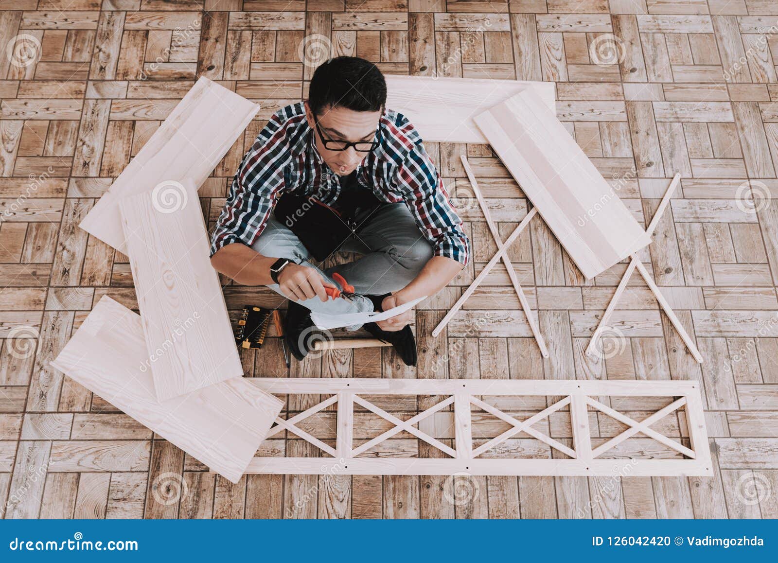 Young Man Assembling Wooden Bookshelf At Home Stock Photo Image