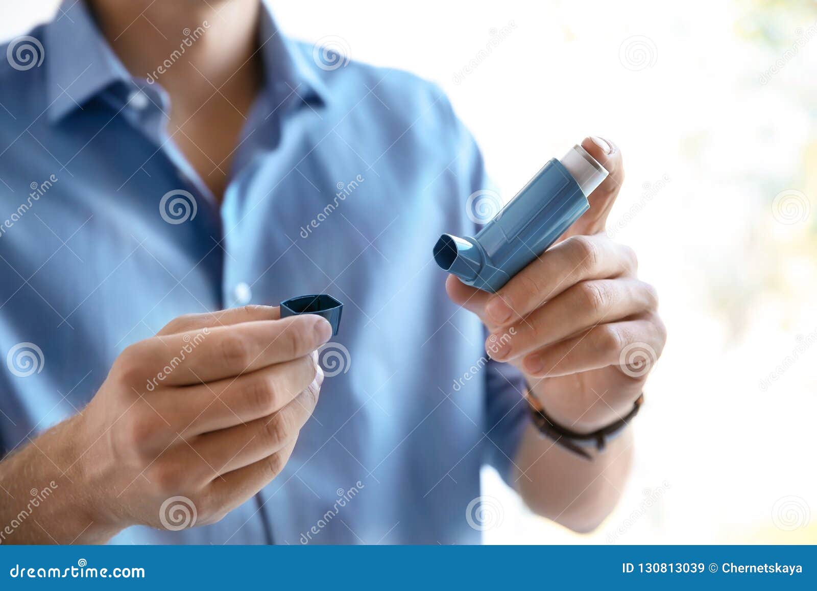 young man with asthma inhaler indoors