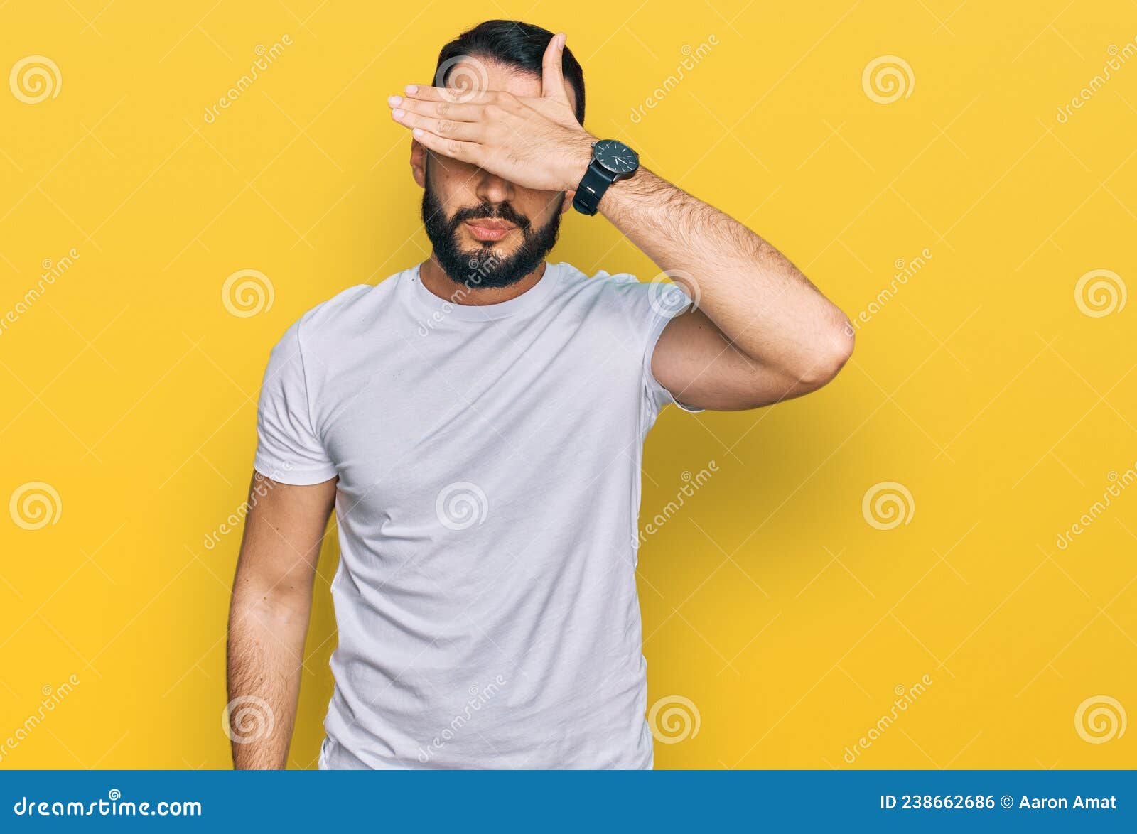 Young Man With Beard Wearing Casual White T Shirt Covering Eyes With