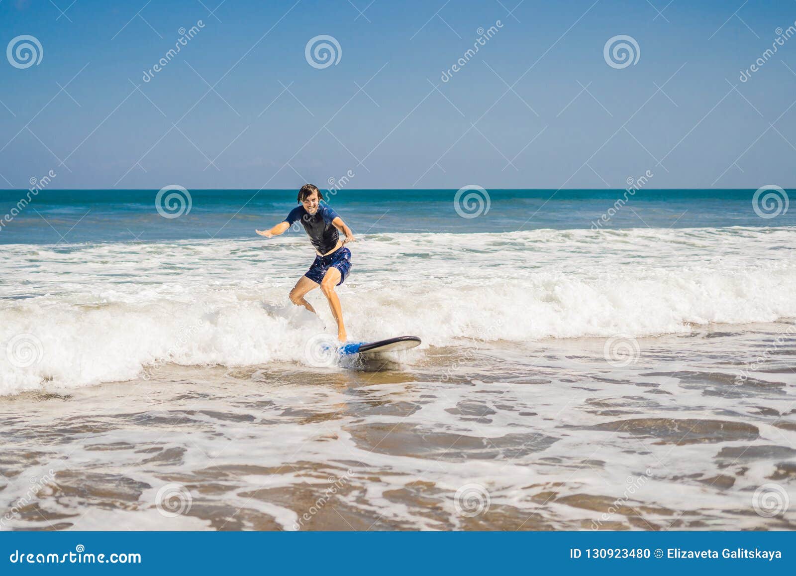 Young Man Beginner Surfer Learns To Surf On A Sea Foam On Young Man Beginner Surfer Learns To Surf On A Sea Foam On