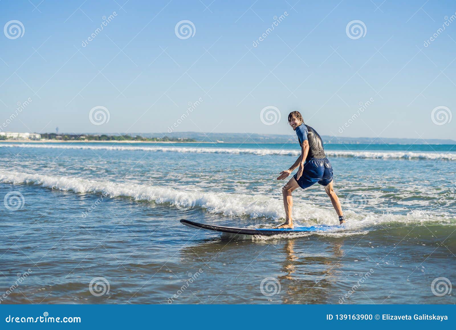 Young Man Beginner Surfer Learns To Surf On A Sea Foam On Young Man Beginner Surfer Learns To Surf On A Sea Foam On