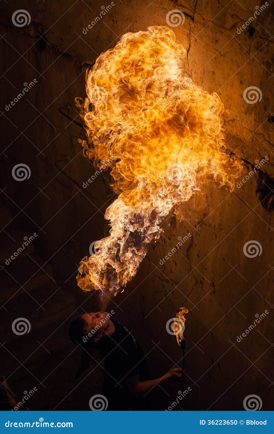 Young man blowing fire from his mouth. Fire artist blowing fire from his mouth
