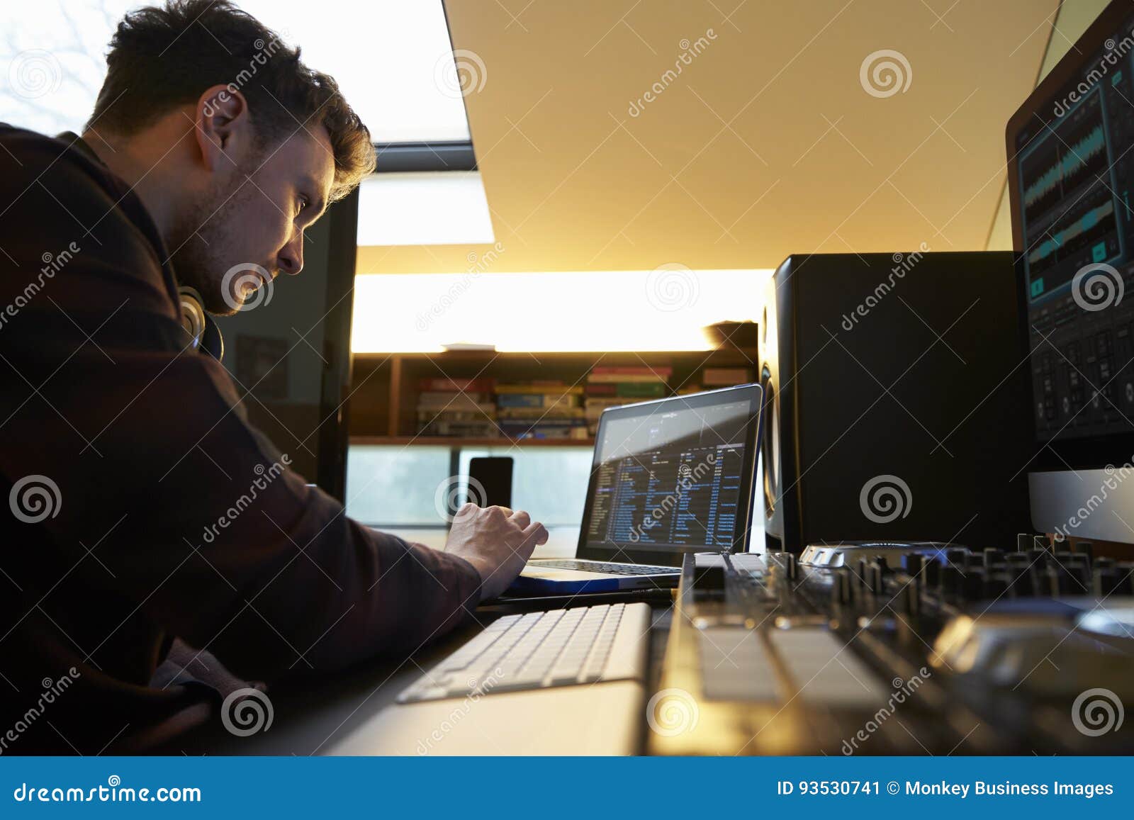 Young Man Composing Music on Laptop Computer in Bedroom Stock Image