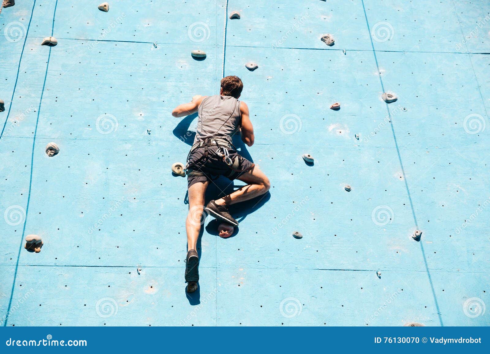 Young Man Doing Exercise in Mountain Climbing on Practice Wall Stock