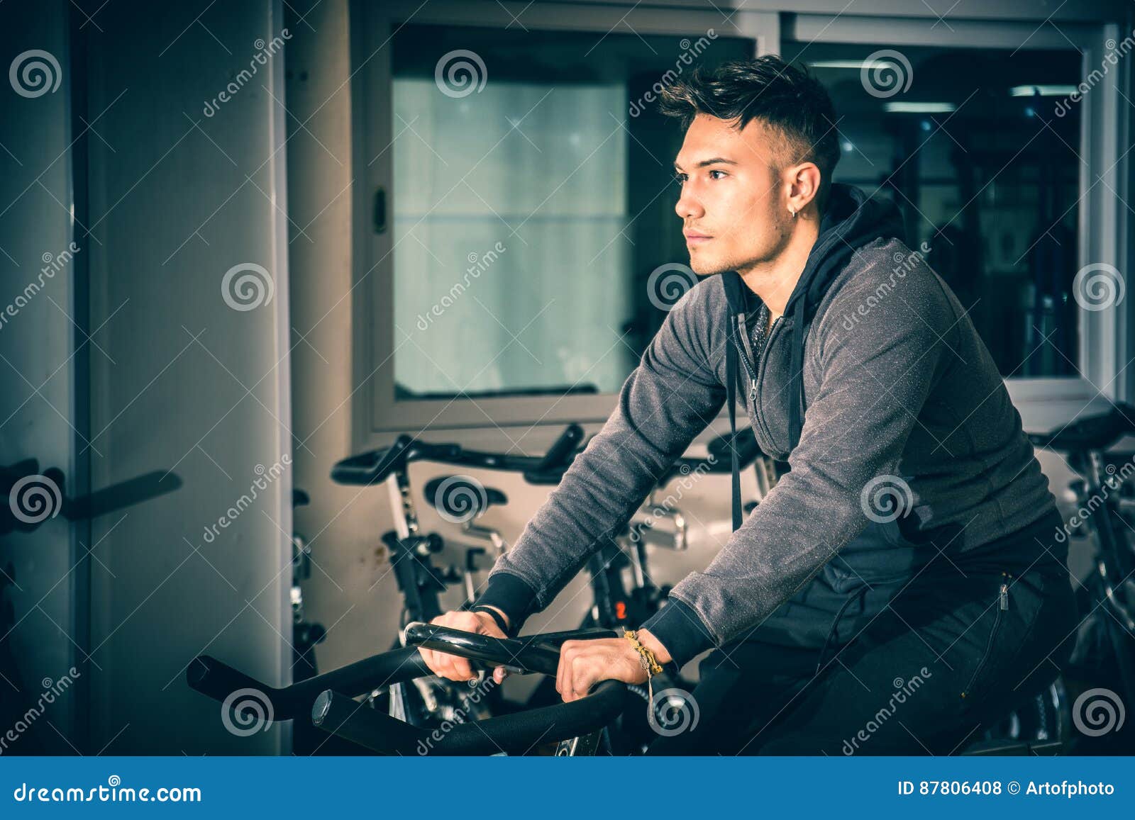 young man exercising in gym: spinning on stationary bike