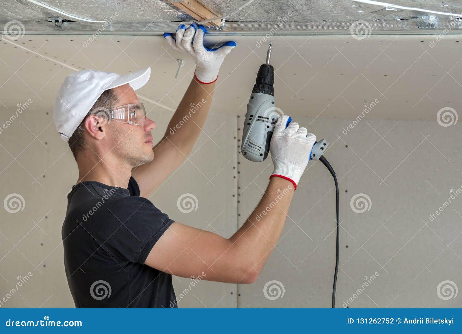 Young Man In Goggles Fixing Drywall Suspended Ceiling To