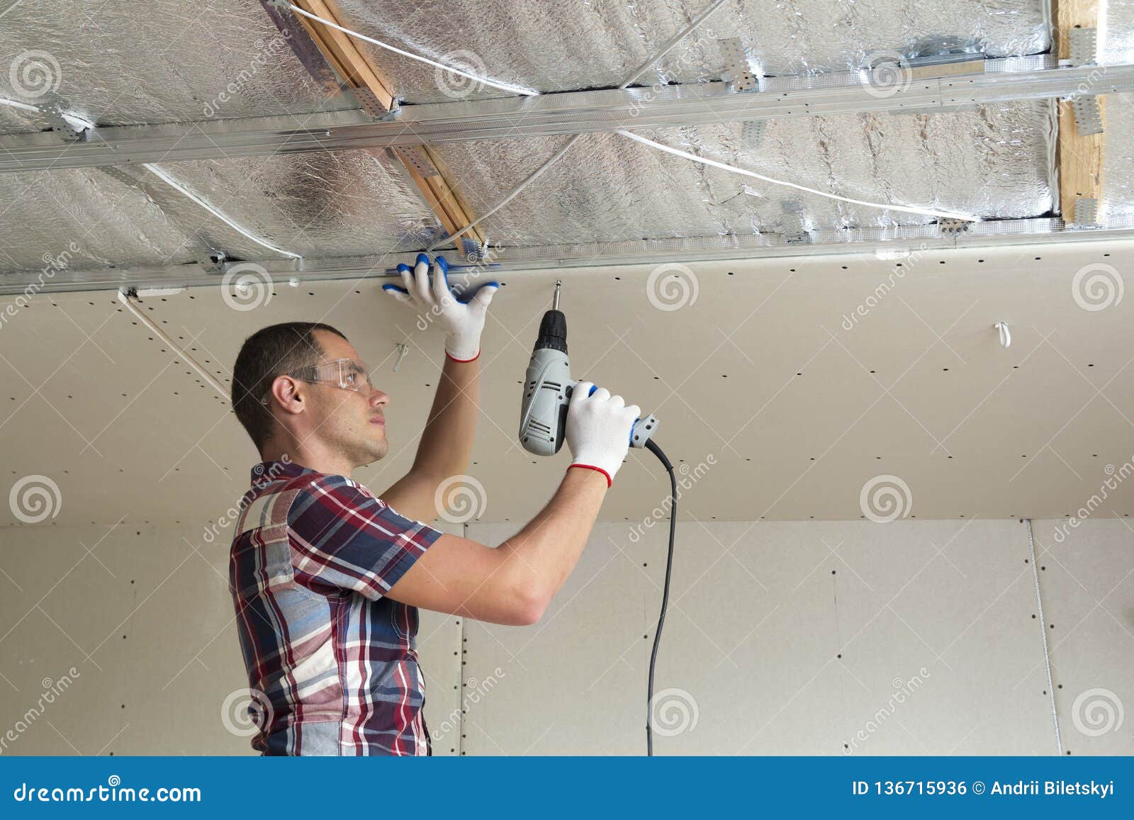 Young Man In Goggles Fixing Drywall Suspended Ceiling To Metal