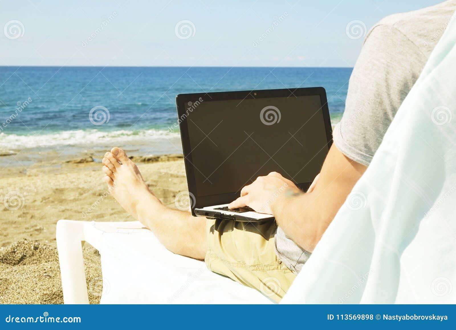 Young Man in Grey Shirt Sitting at the Beach, Working on Laptop ...