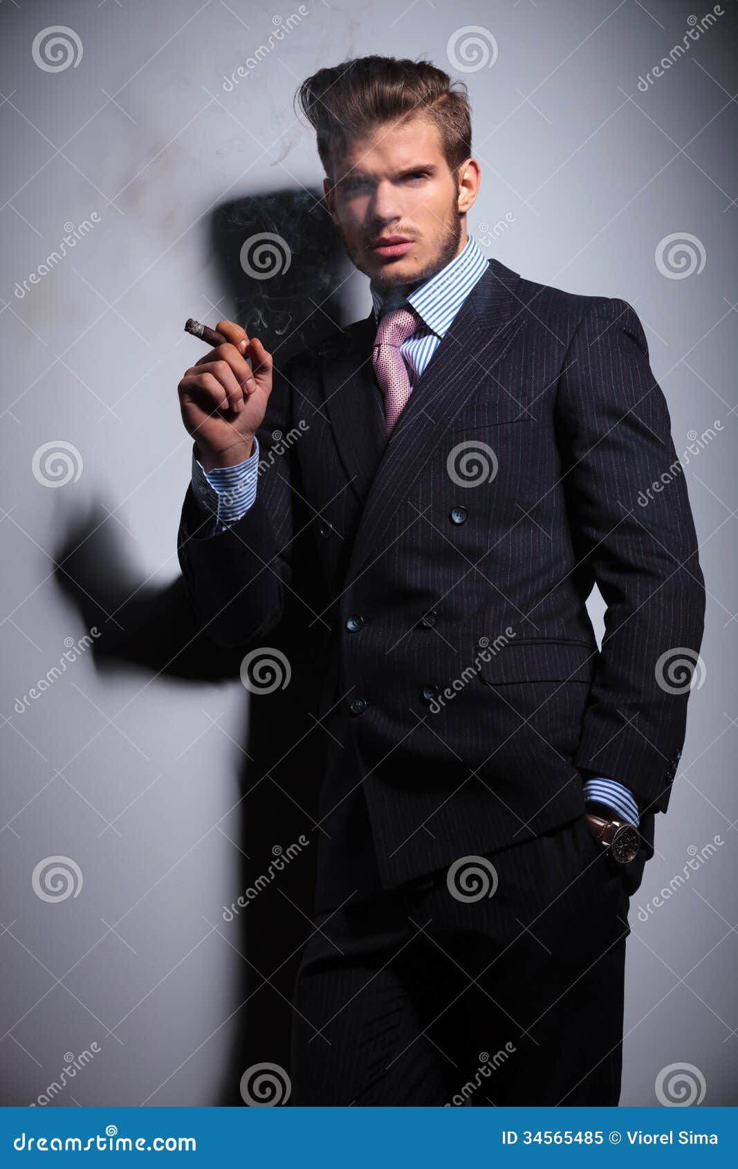 Young Man With Hand In Pocket Is Smoking A Cigar Stock 