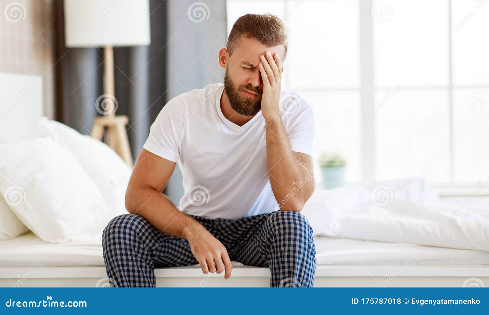 Young Man with a Headache, Was Sick in Bed in Bedroom Stock Photo