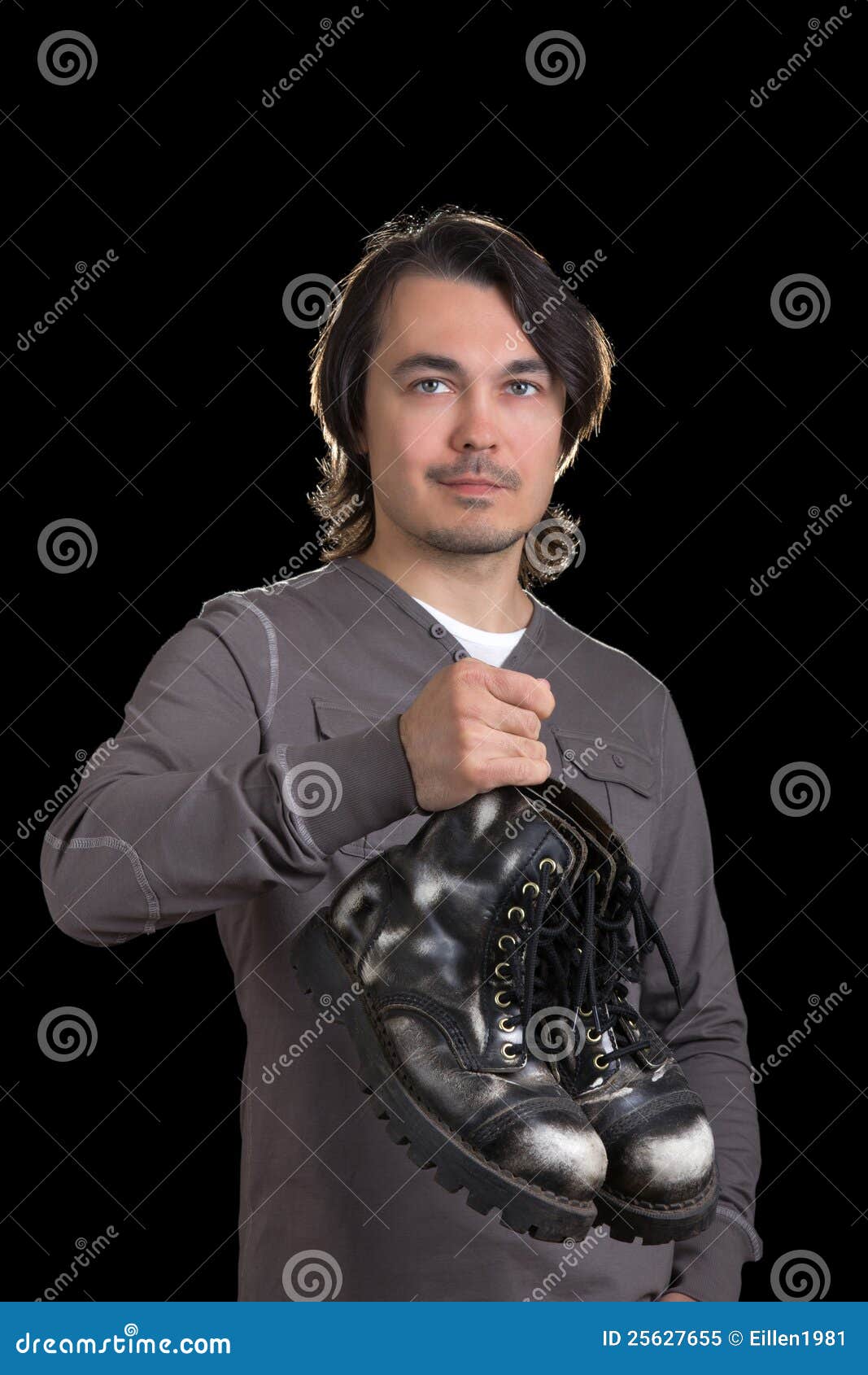 Young Man Holding Old Black Boots In 