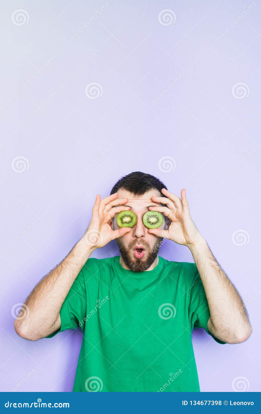 Young Man Holding Slices of Kiwi in Front of His Eyes Stock Photo ...