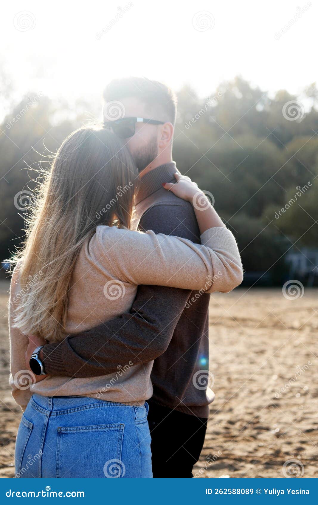 A Young Man Hugs a Girl by the Waist. Couple Standing with Their