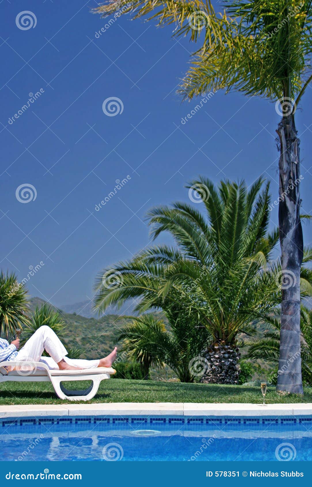 young man lying on a sunbed holding a glass of champagne