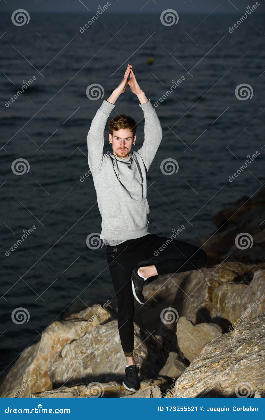 young man in a namaste greeting position while freeing his mind from worries in tree pose
