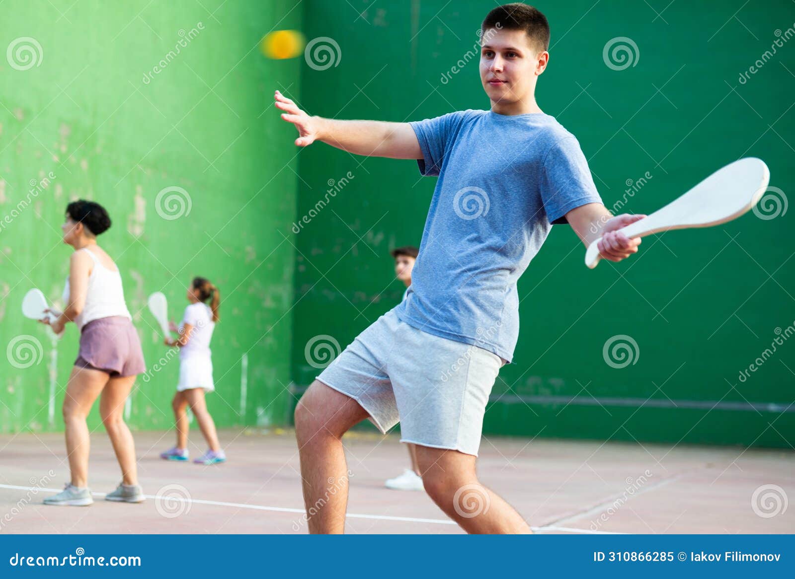 young man playing basque pelota on outdoor pelota court