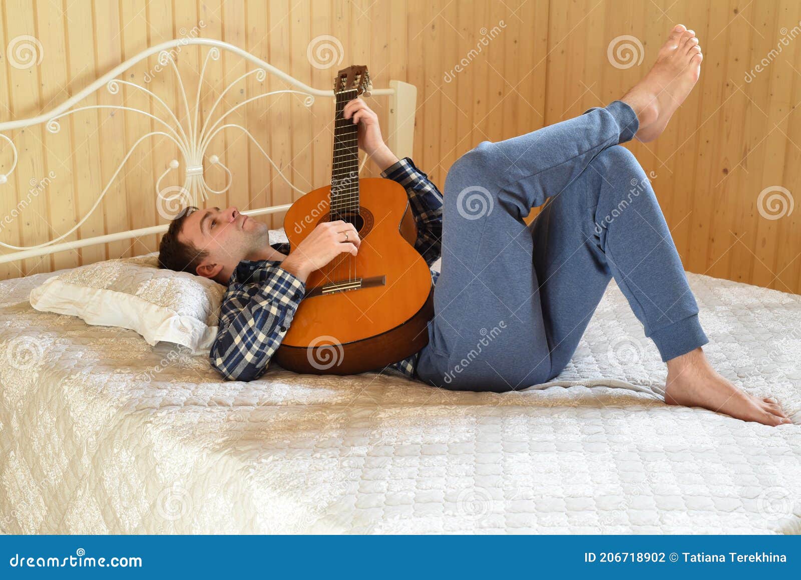 Young Man Playing Guitar and Laying on Bed on Weekend Morning Stock