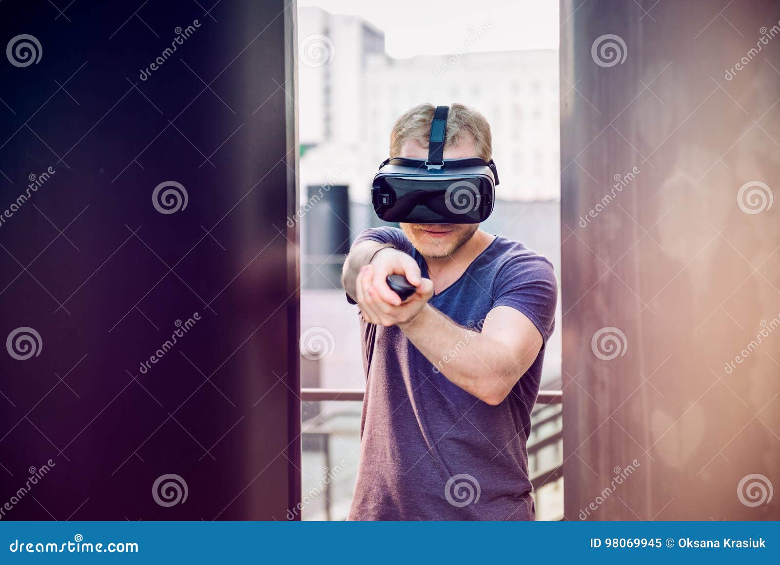 Young Man Playing Shooting Games in Virtual Reality Headset on the Urban Building Background Outdoors