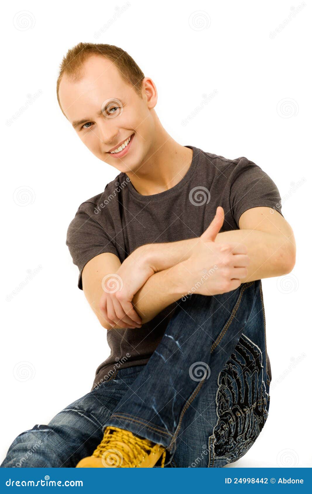 Young man portrait. Young man sits and smiling friendly with hands on his knees on white background