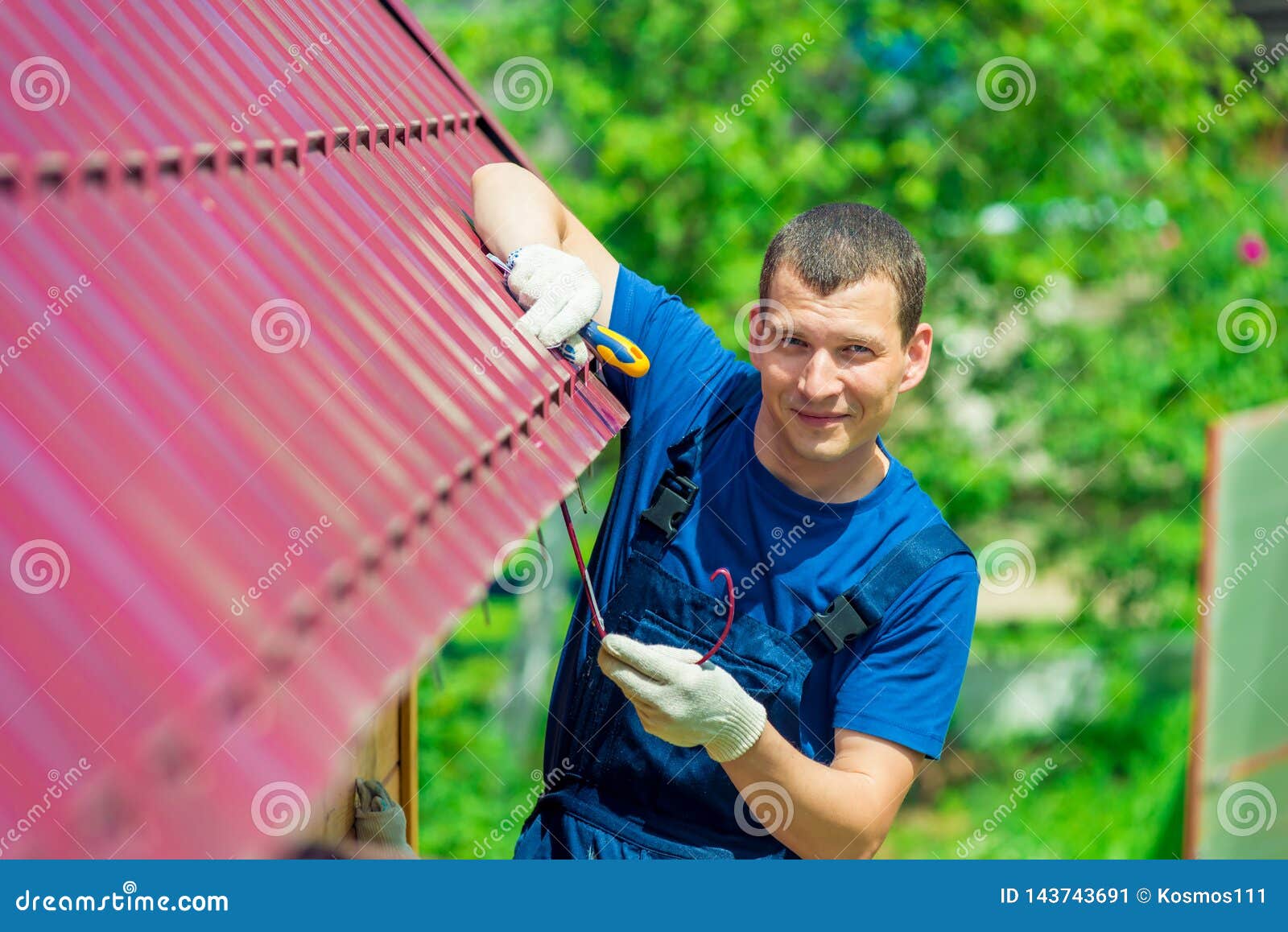 a young man repairs the roof of the house in overalls