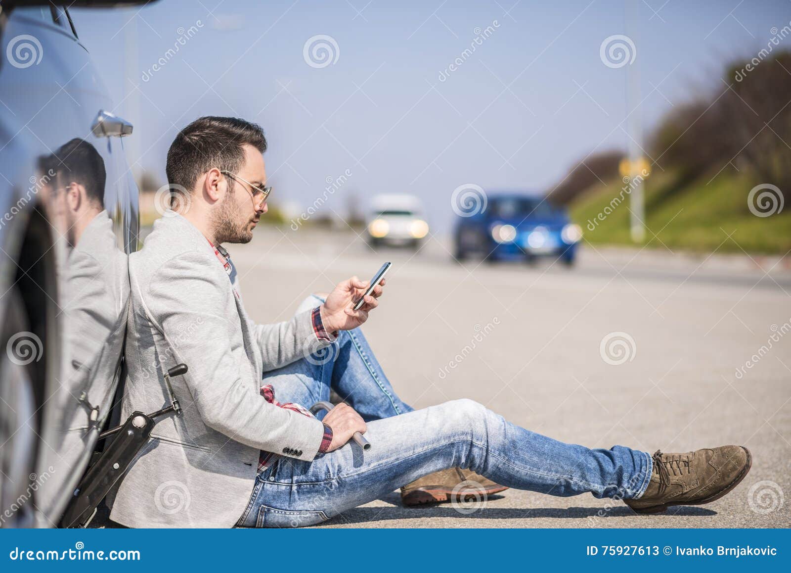 young man with a silver car that broke down on the road