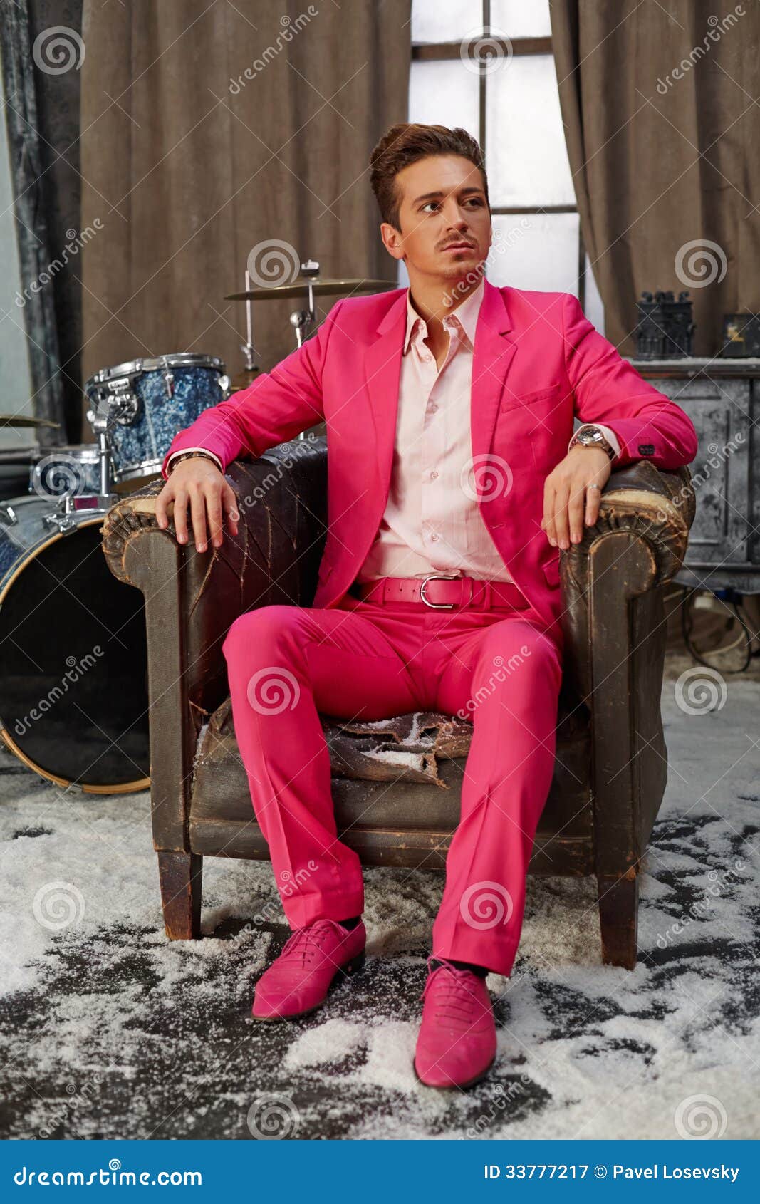 young man sits in scuffed old armchair