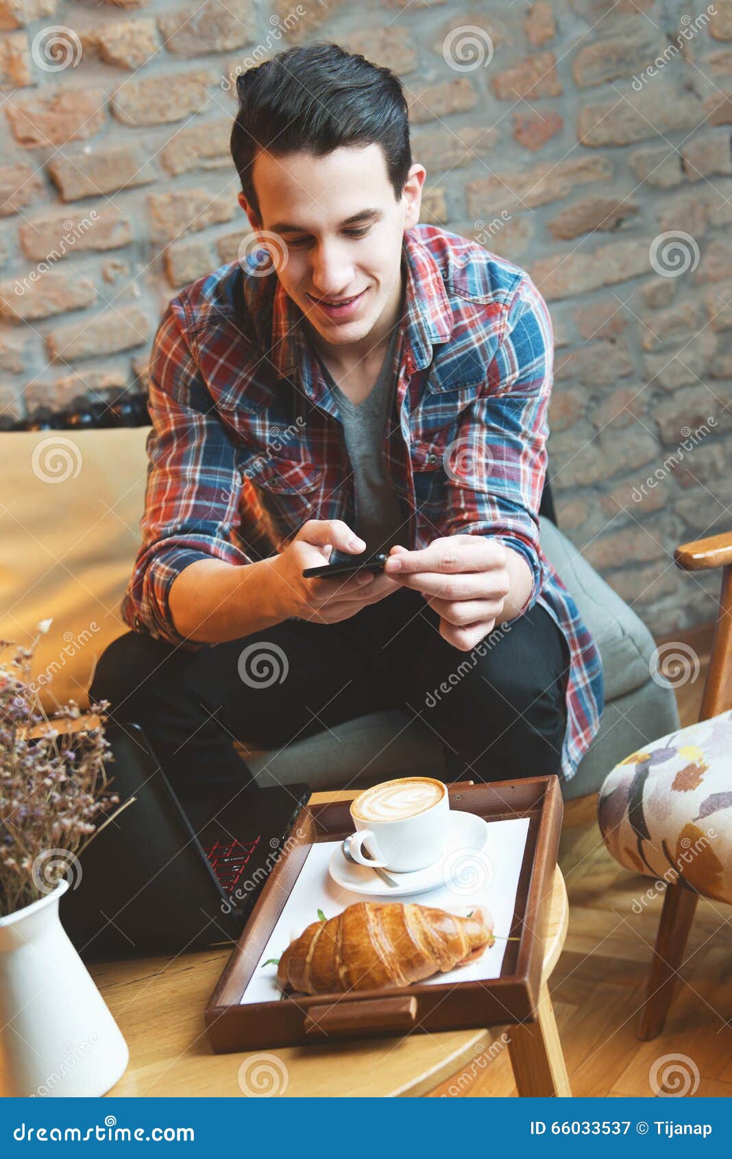 young man sitting at a cafe, taking a snapshot of his food