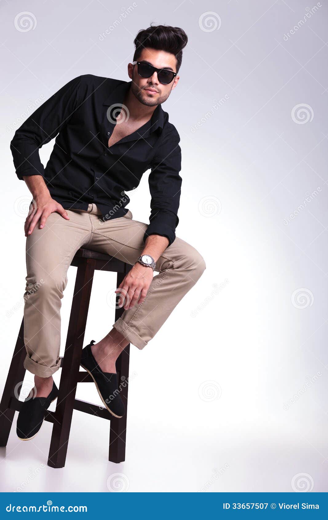 Fashionable gay man in suit and sunglasses posing with chair on grey  background,stock image Stock Photo - Alamy