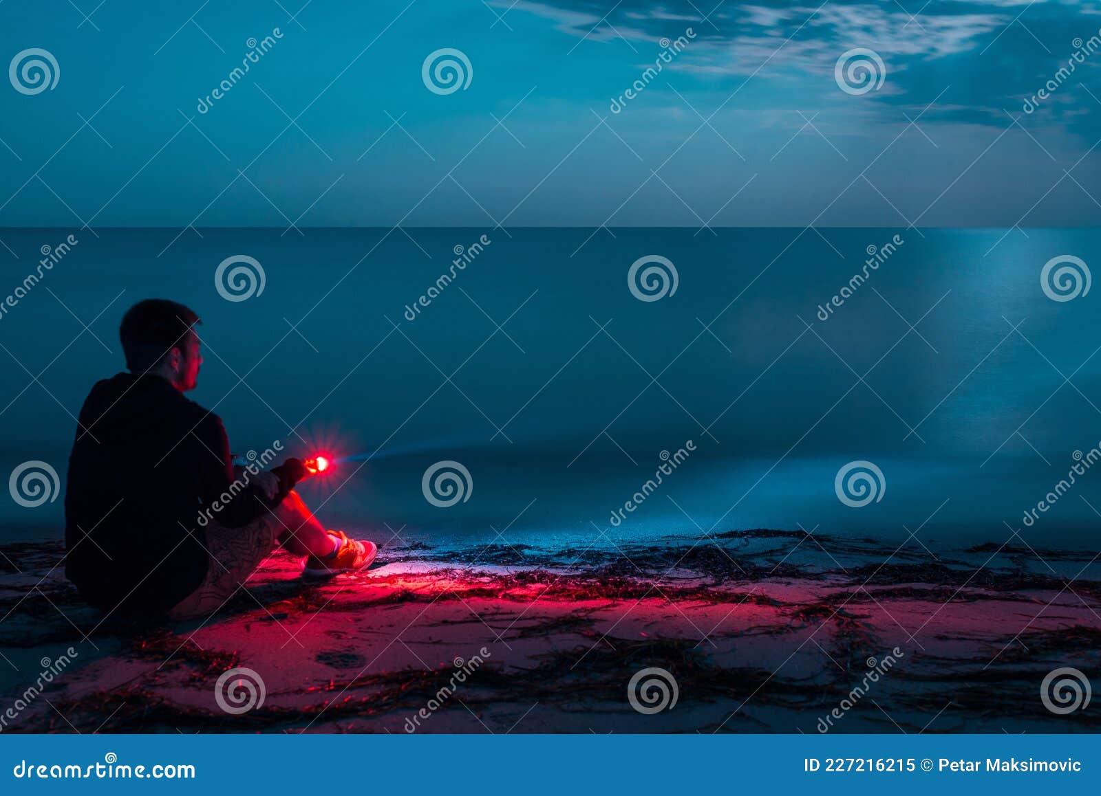 Young Man Sitting on Moonlit Beach with Flashlight, Long Exposure Stock Image Image of