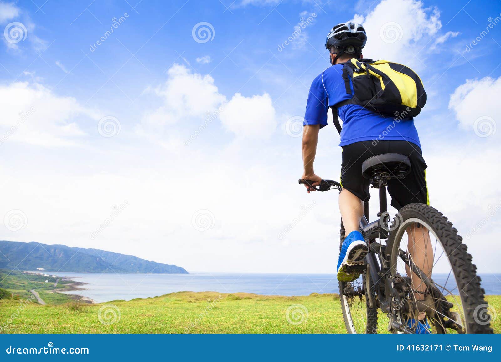 young man sitting on a mountain bike and looking the ocean