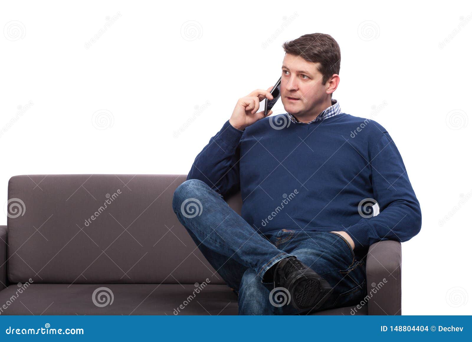 Young Man Sitting on Sofa and Talking on Phone, Isolated on White Stock