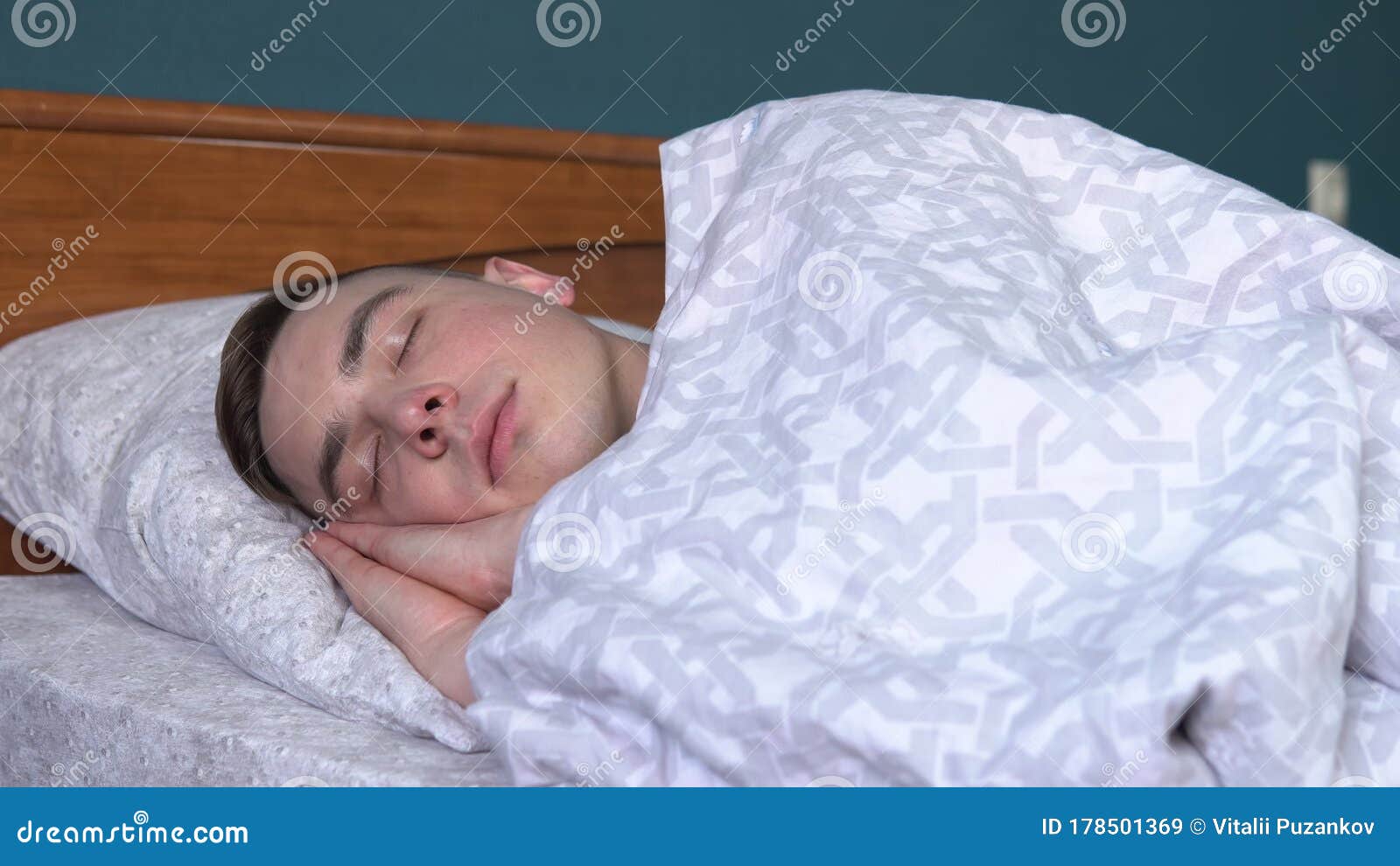 A Young Man is Sleeping Under the Covers. a Man Lies in Bed in His Room