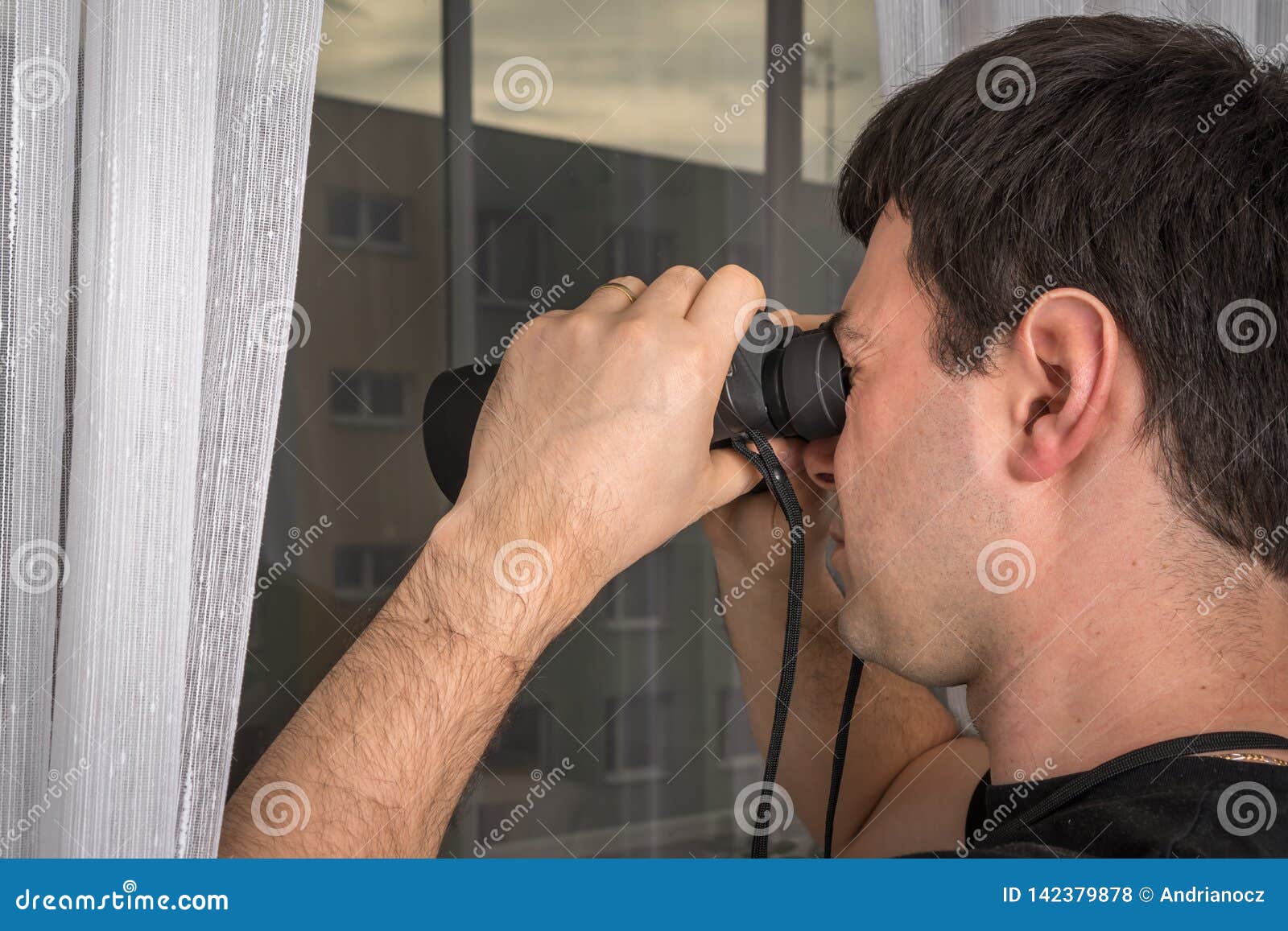 man is spying his neighbours with binoculars