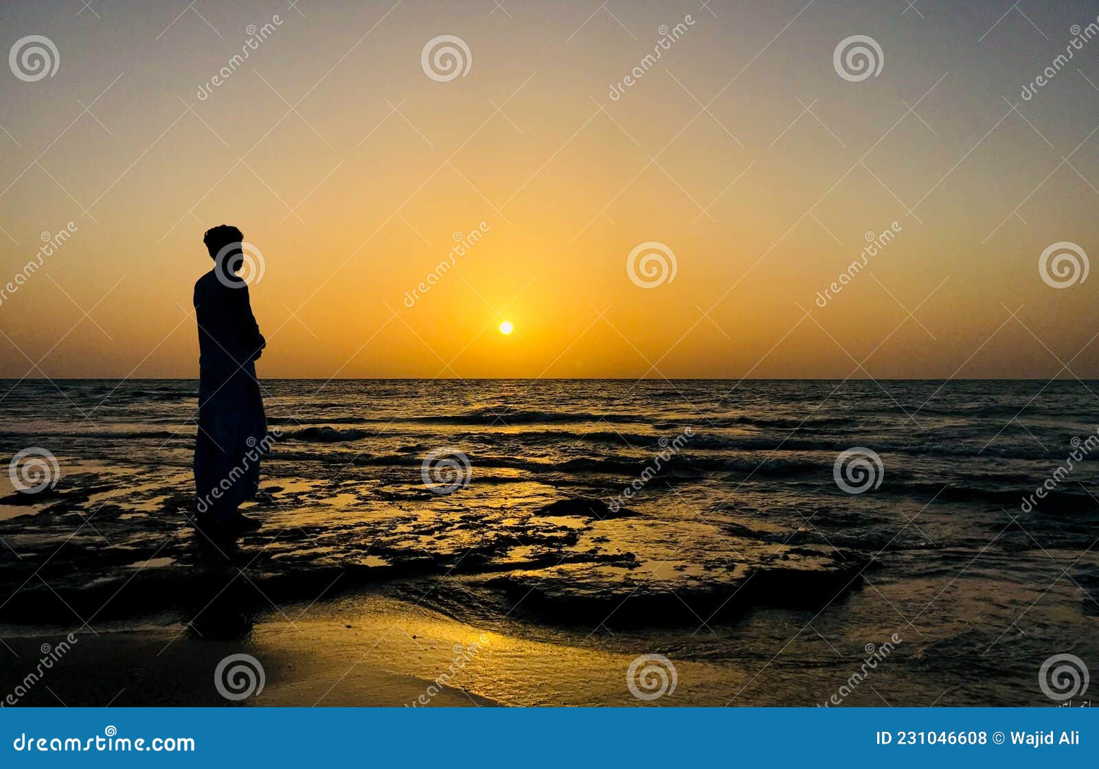 A Young Man Standing at Beach in Front of Sunrise. Sad Expression ...