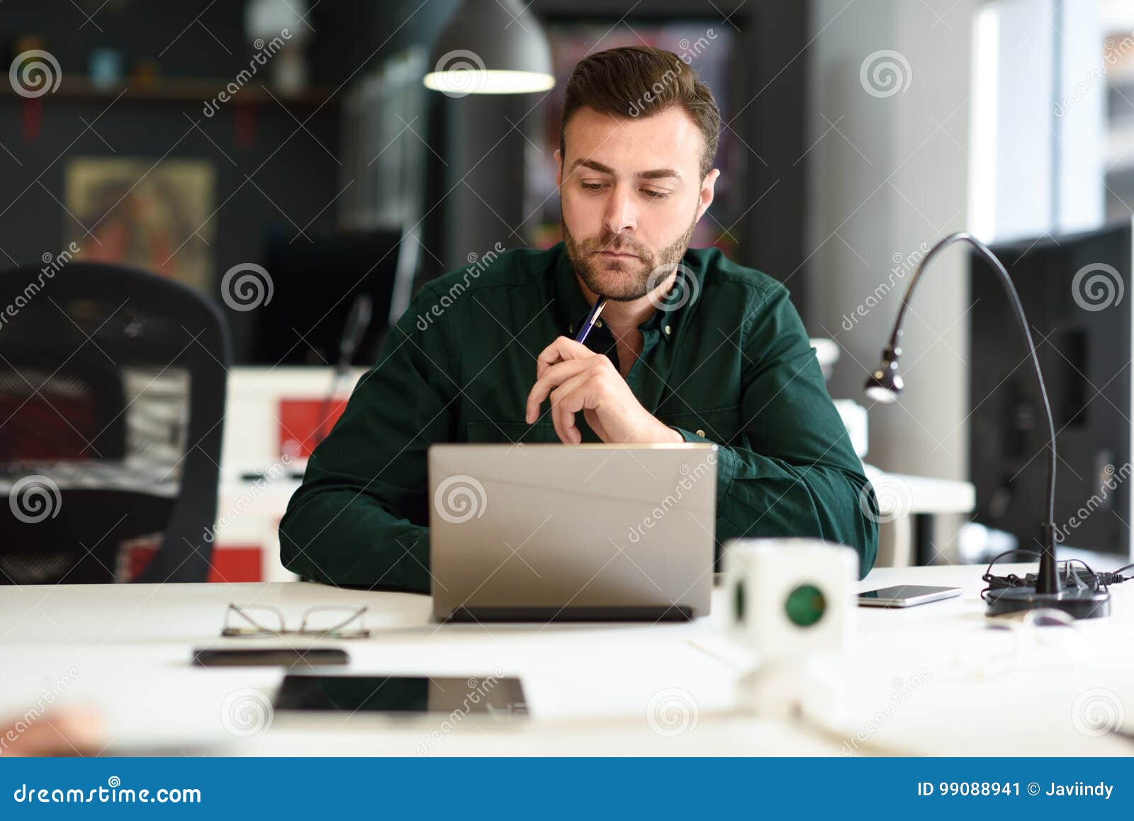 young man studying with laptop computer on white desk.