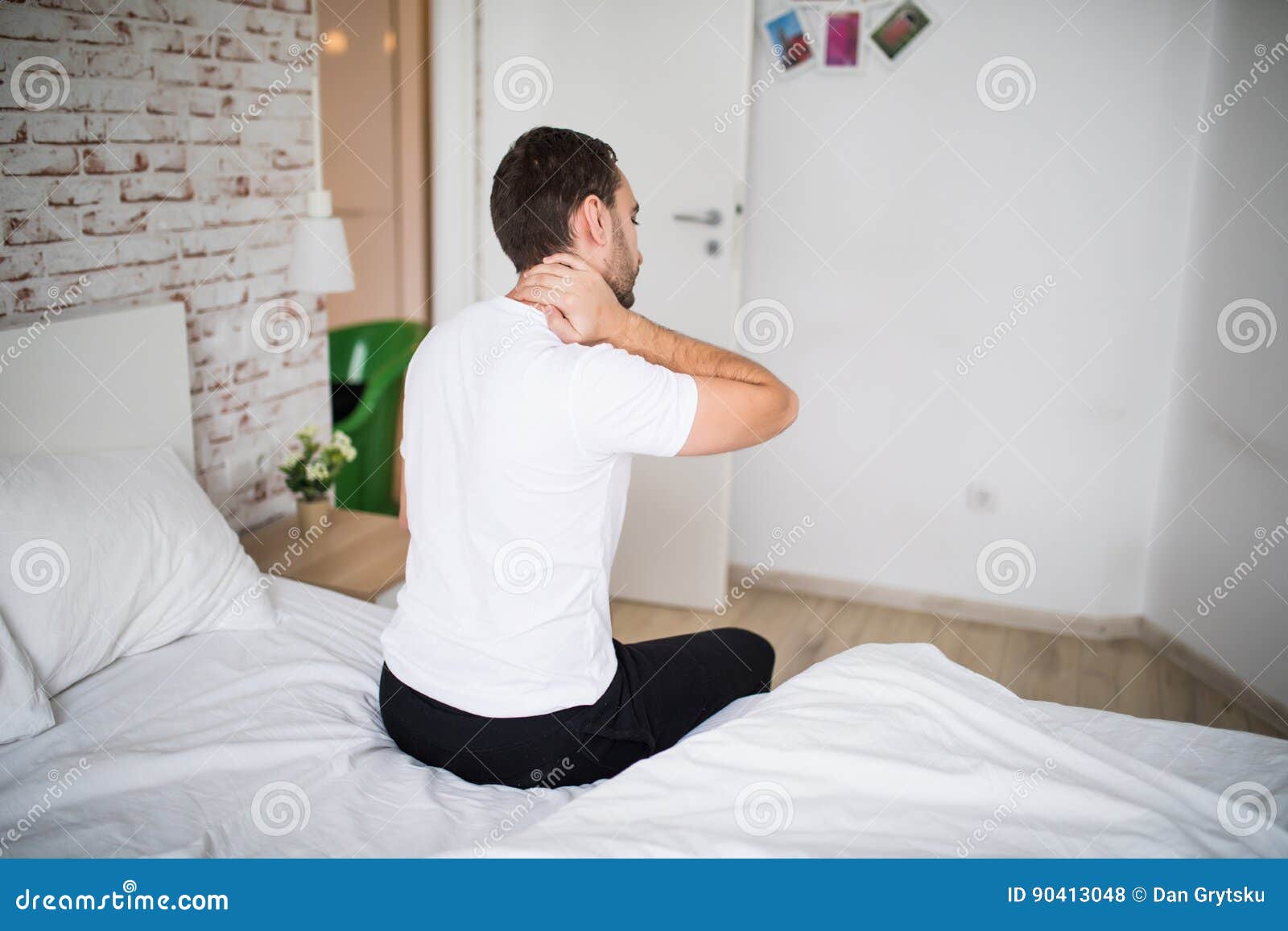 Young Man Suffering from Neck Ache in Bed at Home Stock Photo Image