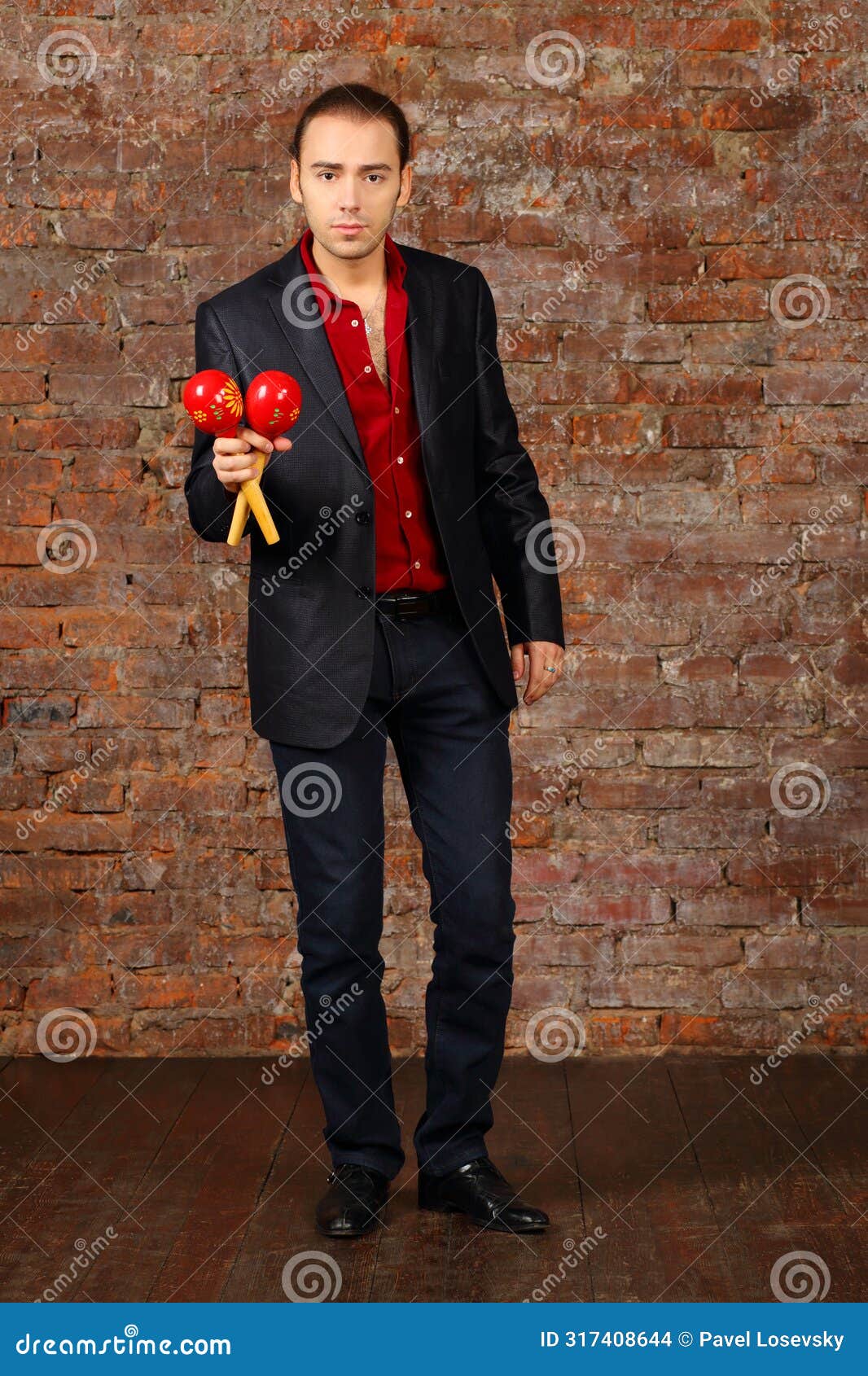 young man in suit stands with maracas in studio