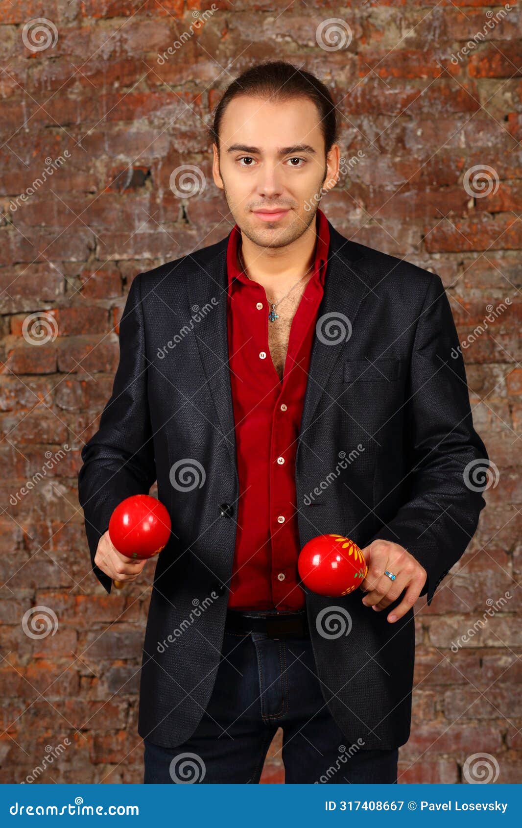 young man in suit stands with red maracas in