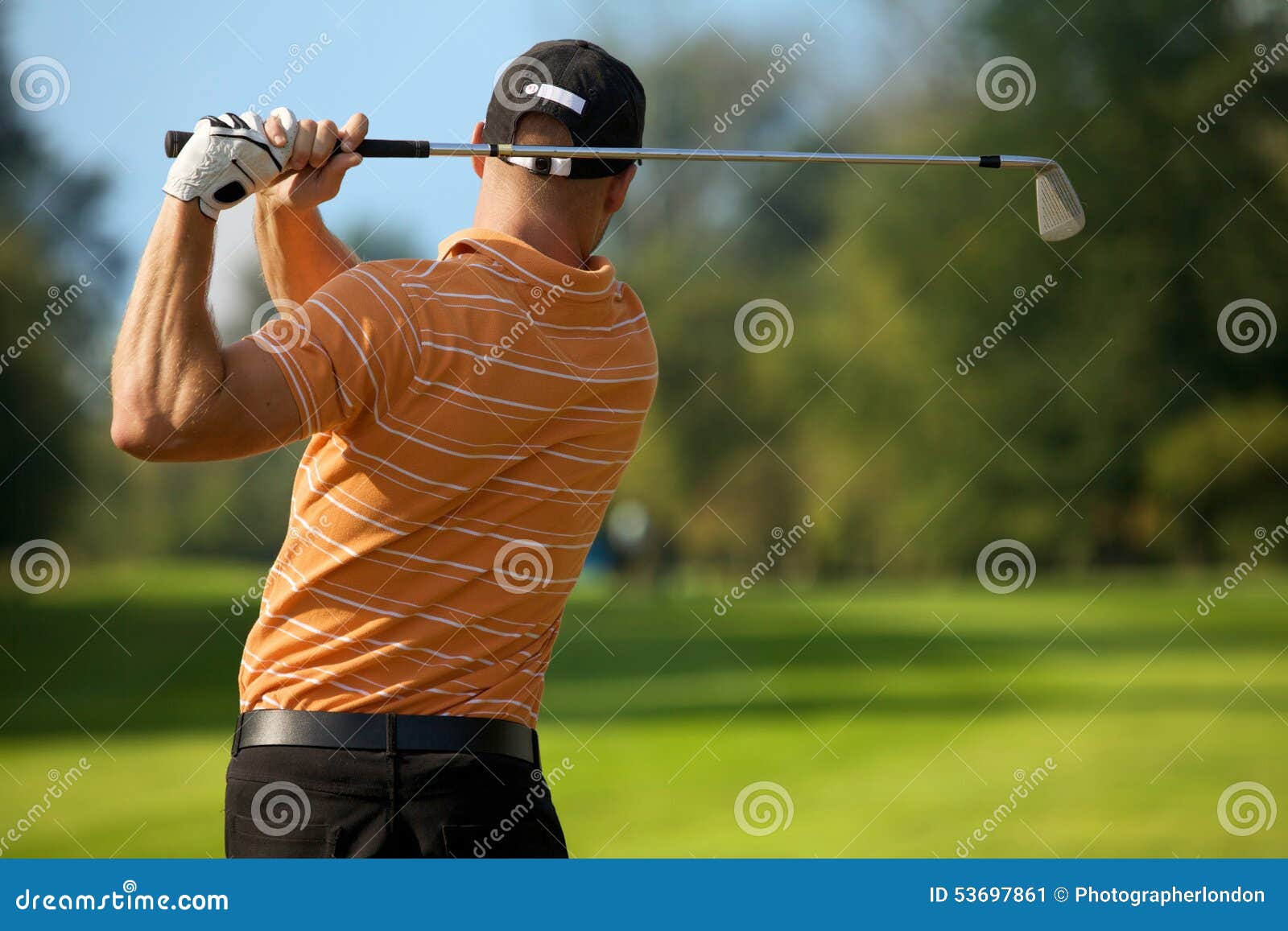 young man swinging golf club, rear view