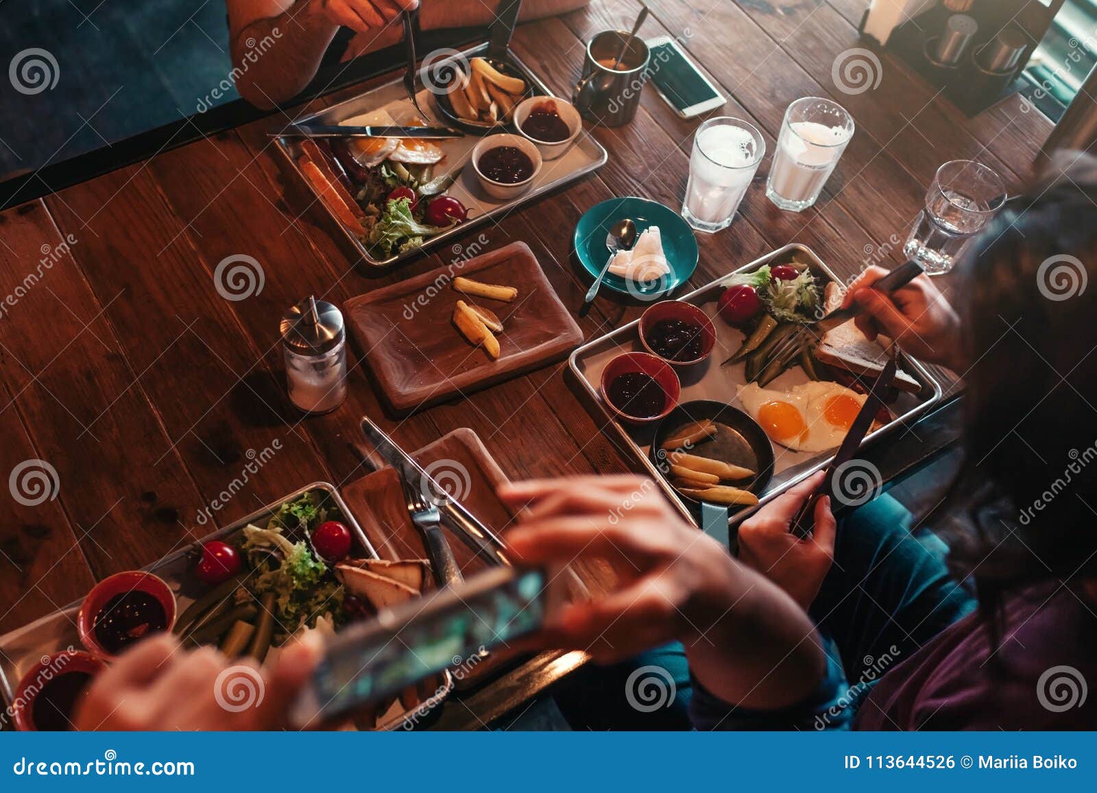 young man takes a picture of his food for social network while having breakfast in cafe. internet addiction concept.