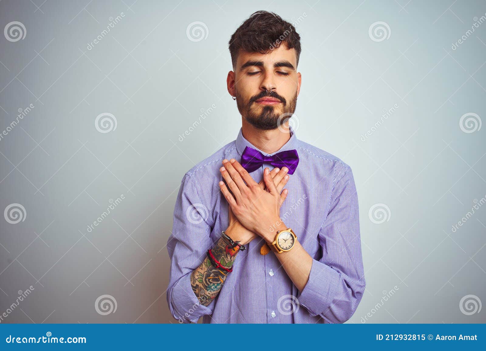 Young Man with Tattoo Wearing Purple Shirt and Bow Tie Over Isolated White Background Smiling with Hands on Chest with Closed Eyes Stock Image - Image of isolated, casual: 212932815