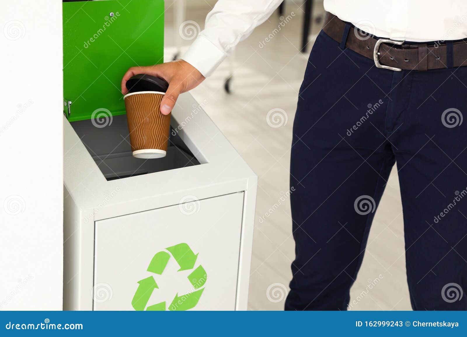 Young Man Throwing Coffee Cup into Recycling Bin in Office Stock Image