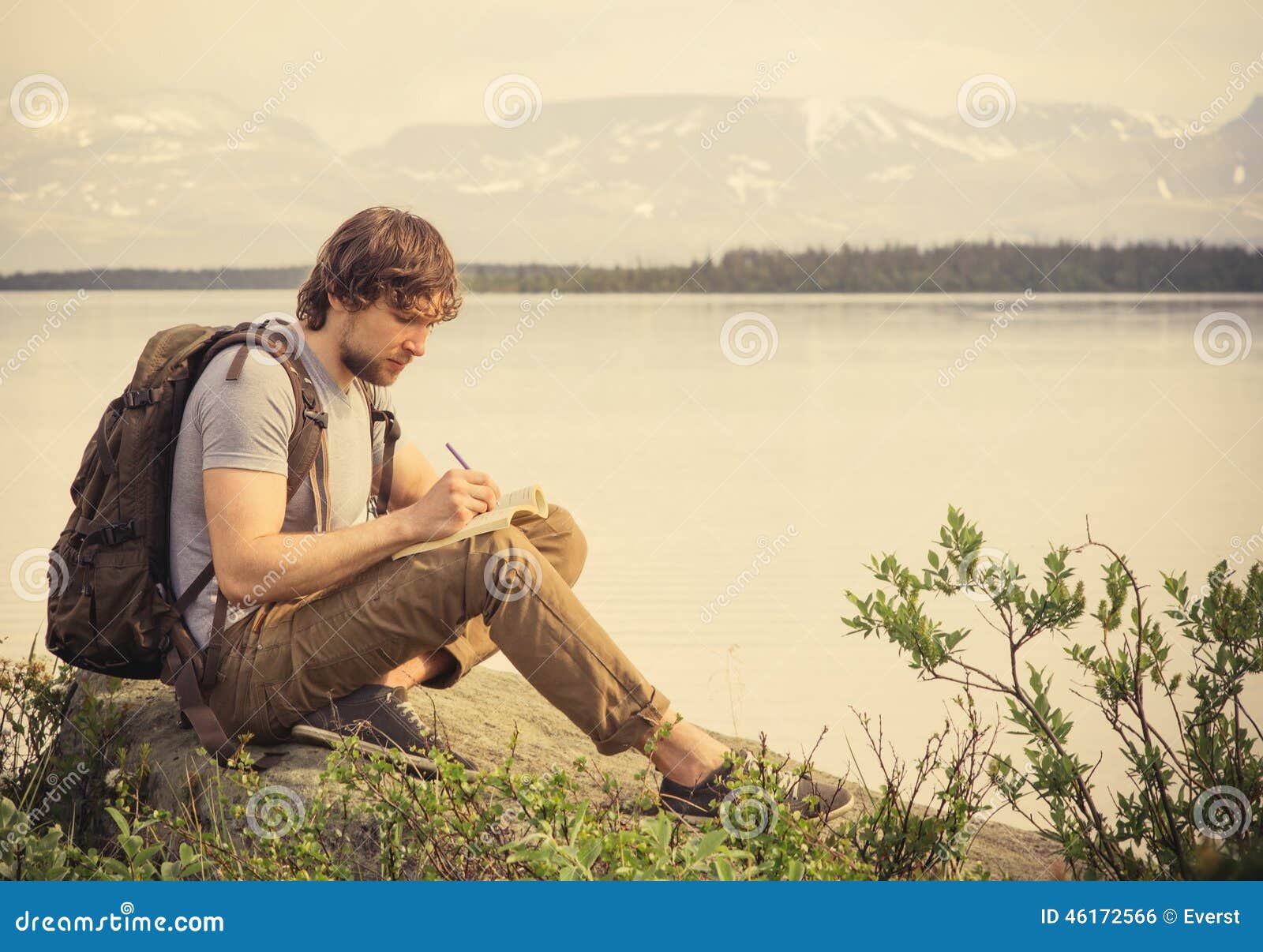 young man traveler with backpack reading book