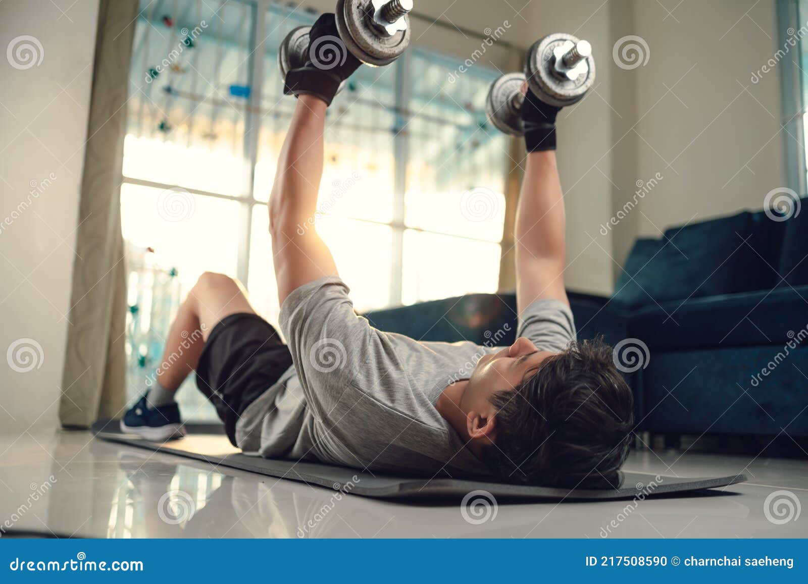 Young Man Use Dumbbell Exercises Chest Fly on Yoga Mat in Living