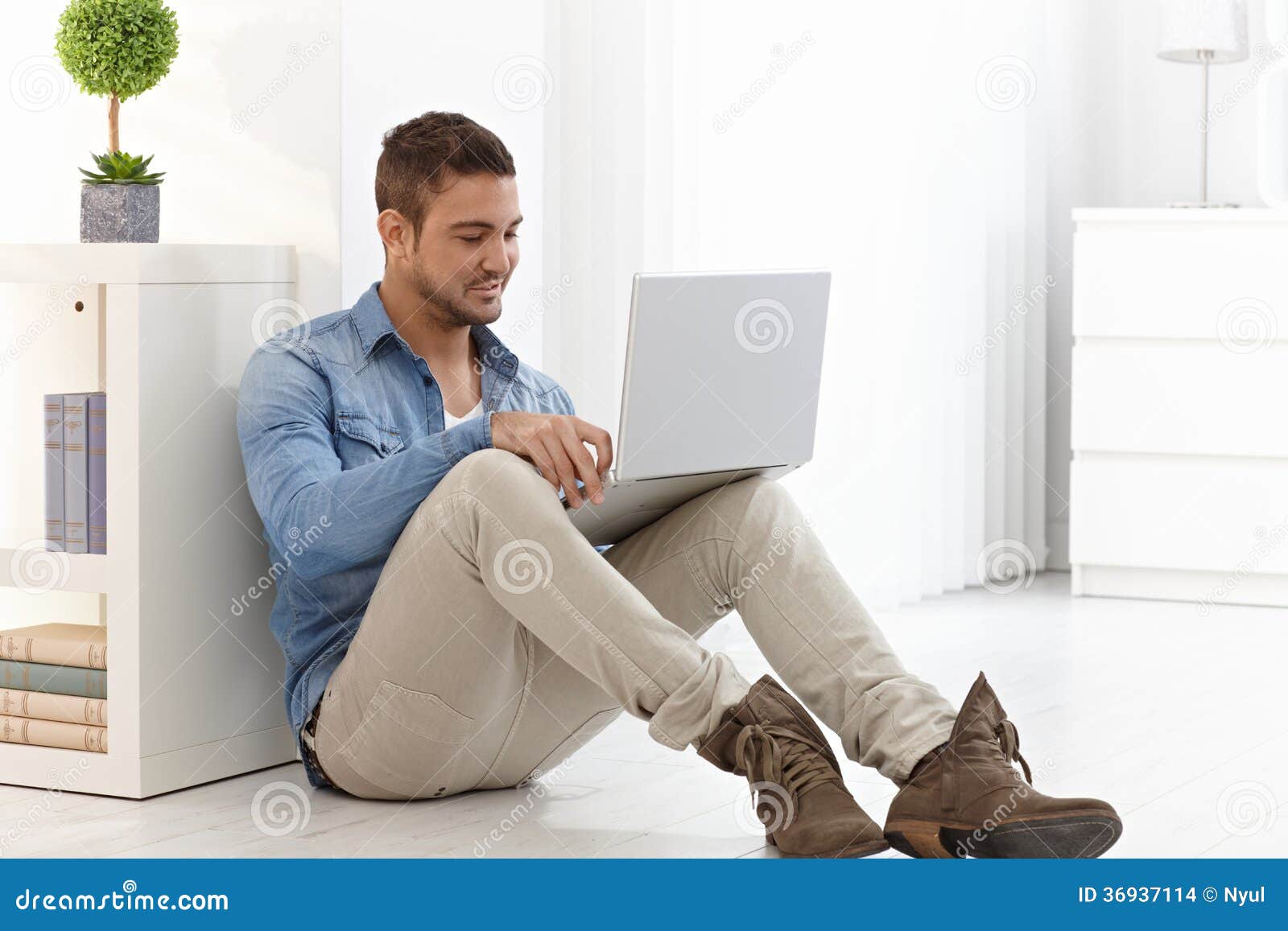 Young man using laptop at home. Young man sitting on floor at home, using laptop computer.